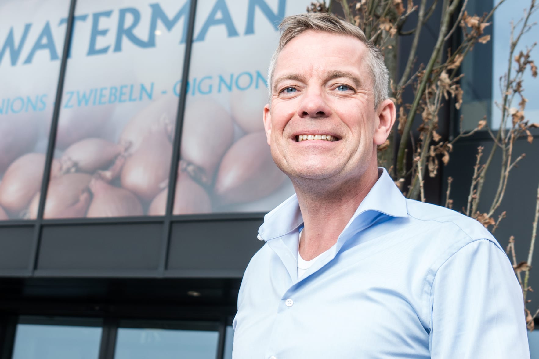 Erik Waterman voor zijn bedrijf lachend. 